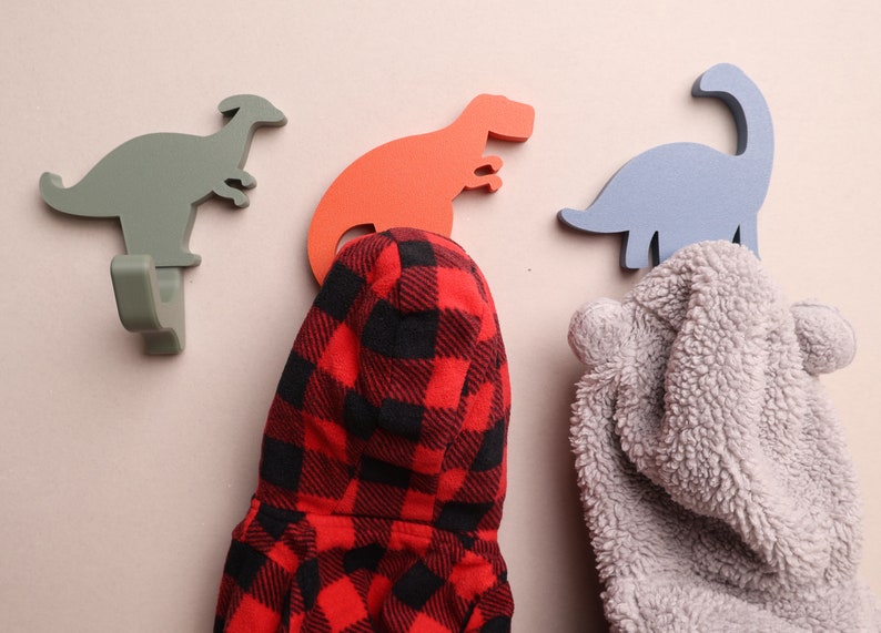 3 dinosaur wall hooks with coats on them