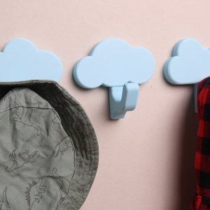 3 cloud wall hooks with a hat and coat hanging on them