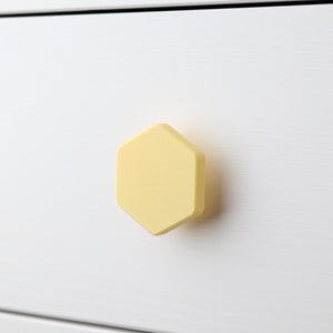 May include: A white drawer with a yellow hexagonal cabinet knob.