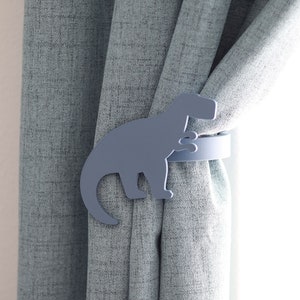 May include: A light blue dinosaur shaped curtain tieback. The tieback is made of metal and has a simple design.