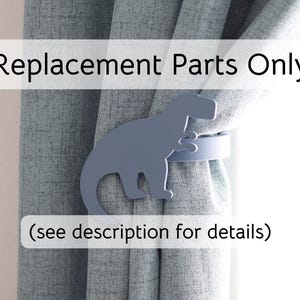May include: A gray dinosaur-shaped curtain tieback holds a curtain in place. The text "Replacement Parts Only" and "(see description for details)" are displayed on the image. The curtain is a light gray color.