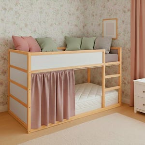 May include: A wooden bunk bed with a white and light brown frame. The bed has a white mattress, a pink curtain, and is decorated with pink, green, and grey cushions. The room has floral wallpaper and a pink curtain.