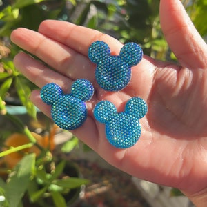 May include: Three blue, sparkly, rhinestone Mickey Mouse head shapes.