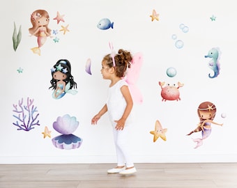 Könnte beinhalten: Aquarell-Wandtattoos mit Meerjungfrauen, Seesternen, Korallen und Meeresbewohnern in Blau-, Rosa-, Lila- und Gelbtönen. Ein junges Kind mit Feenflügeln ist im Bild.
