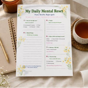May include: A printable PDF page titled "My Daily Mental Reset" with floral accents. The page includes prompts for self-reflection and a daily reset routine. The image also shows a cup of tea, a pen, and a notebook.