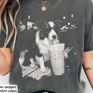 May include: Pepper-colored t-shirt featuring a black and white graphic of a dog wearing sunglasses and drinking from a clear iced coffee cup. The shirt is made of comfort colors material.