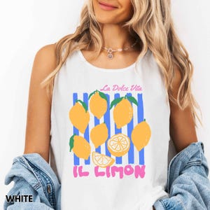 May include: White tank top with a graphic of yellow lemons, blue stripes, and the text "La Dolce Vita" and "Il Limon" in pink. The shirt is sleeveless.