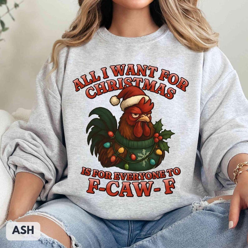 May include: Ash gray sweatshirt with a Christmas rooster graphic. The rooster wears a Santa hat and a green sweater with Christmas lights. Text reads "ALL I WANT FOR CHRISTMAS IS FOR EVERYONE TO F-CAW-F."
