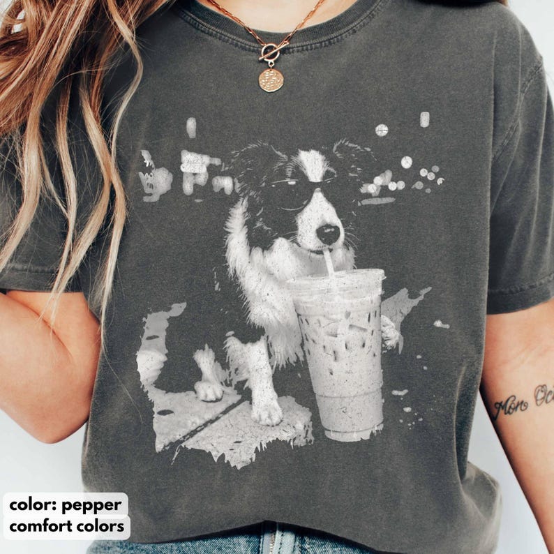 May include: Pepper-colored t-shirt featuring a black and white graphic of a dog wearing sunglasses and drinking from a clear iced coffee cup. The shirt is made of comfort colors material.