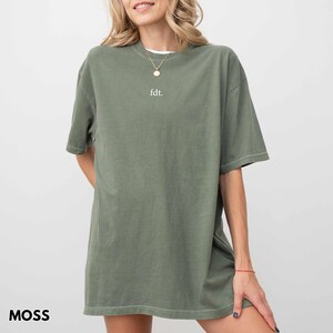 May include: A moss green oversized t-shirt with a white "fdt." text on the front.