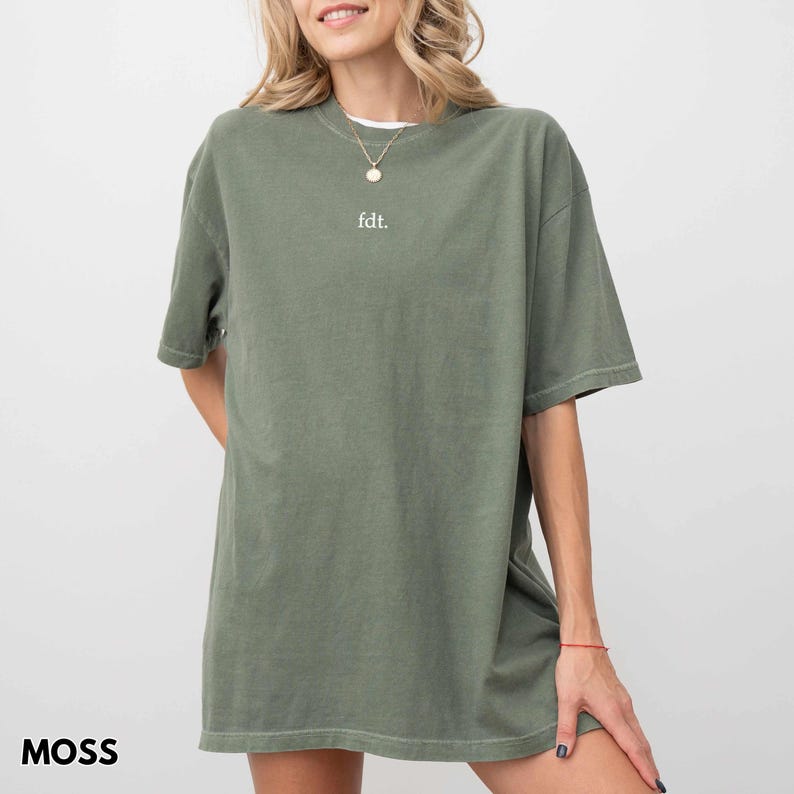 May include: A moss green oversized t-shirt with a white "fdt." text on the front.