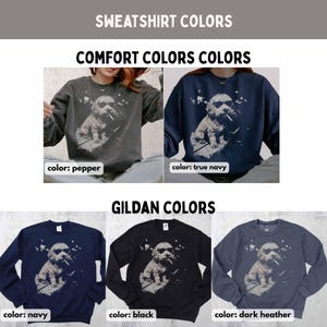 May include: A display of sweatshirts in various colors, including pepper, true navy, navy, black, and dark heather. Each sweatshirt features a graphic of a dog wearing sunglasses and smoking a cigarette. The text "SWEATSHIRT COLORS" and "COMFORT COLORS COLORS" are at the top.