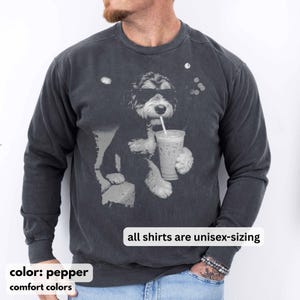 K&ouml;nnte beinhalten: Unisex-Sweatshirt in Pfefferfarbe mit einer Grafik eines Hundes, der eine Sonnenbrille tr&auml;gt und aus einem Becher mit Strohhalm trinkt. Der Text "all shirts are unisex-sizing" wird angezeigt. Die W&ouml;rter "color: pepper" und "comfort colors" sind ebenfalls sichtbar.