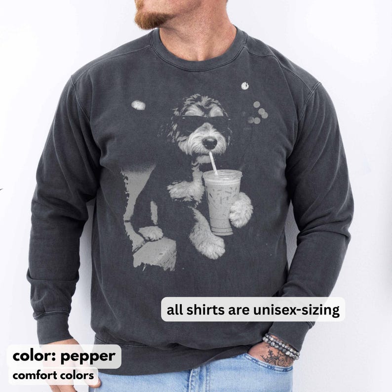 K&ouml;nnte beinhalten: Unisex-Sweatshirt in Pfefferfarbe mit einer Grafik eines Hundes, der eine Sonnenbrille tr&auml;gt und aus einem Becher mit Strohhalm trinkt. Der Text "all shirts are unisex-sizing" wird angezeigt. Die W&ouml;rter "color: pepper" und "comfort colors" sind ebenfalls sichtbar.