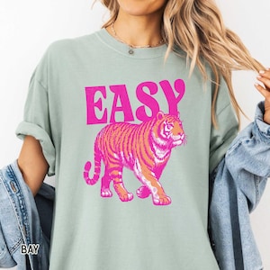 K&ouml;nnte beinhalten: Hellgr&uuml;nes T-Shirt mit dem Wort "EASY" in leuchtend pinkfarbenen Blockbuchstaben &uuml;ber einer rosa-orangenen Tigerillustration. Der Tiger geht nach rechts.