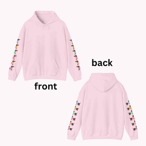 May include: Pink hoodie with a row of colorful dachshund dogs printed on each sleeve. The hoodie has a front pouch pocket and a drawstring hood. The words "front" and "back" are printed below the hoodie images.
