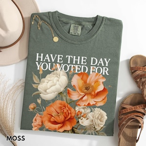 May include: A green t-shirt with a floral design and the text "Have the day you voted for".