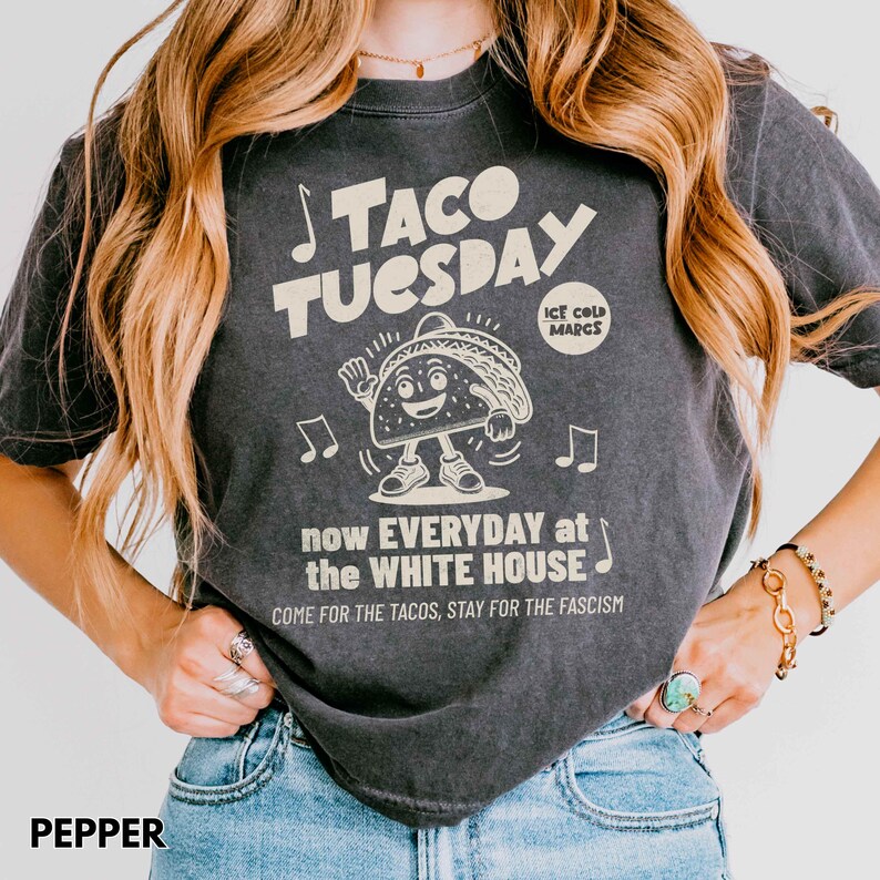 Pode incluir: Camiseta cinza escuro com o texto "TACO TUESDAY" e um personagem de desenho animado de taco. A camisa tamb&eacute;m apresenta o texto "now EVERYDAY at the WHITE HOUSE" e "COME FOR THE TACOS, STAY FOR THE FASCISM".