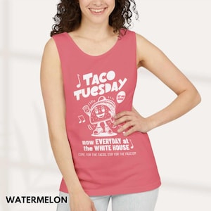 May include: Watermelon-colored tank top with a white graphic that reads "TACO TUESDAY" and features a cartoon taco character. The text "now EVERYDAY at the WHITE HOUSE" and "COME FOR THE TACOS, STAY FOR THE FASCISM" is also printed on the shirt.