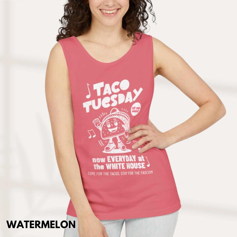 May include: Watermelon-colored tank top with a white graphic that reads "TACO TUESDAY" and features a cartoon taco character. The text "now EVERYDAY at the WHITE HOUSE" and "COME FOR THE TACOS, STAY FOR THE FASCISM" is also printed on the shirt.