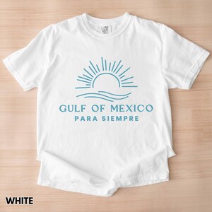 May include: White t-shirt with a blue graphic of a sun rising over waves and the text "GULF OF MEXICO PARA SIEMPRE".