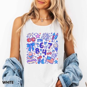 Puede incluir: Camiseta sin mangas blanca con un dise&ntilde;o gr&aacute;fico colorido que presenta s&iacute;mbolos patri&oacute;ticos como fuegos artificiales, la bandera estadounidense, estrellas y el n&uacute;mero "1776". El dise&ntilde;o incorpora colores rojo, blanco y azul, perfecto para celebraciones del D&iacute;a de la Independencia.