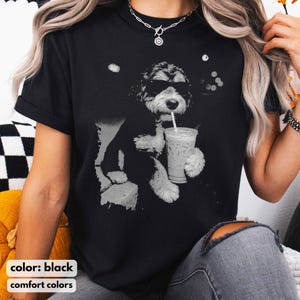 K&ouml;nnte beinhalten: Schwarzes T-Shirt mit einer schwarz-wei&szlig;en Grafik eines Hundes mit Sonnenbrille, der ein Getr&auml;nk mit Strohhalm h&auml;lt. Der Text "color: black" und "comfort colors" befindet sich am unteren Rand des Shirts.