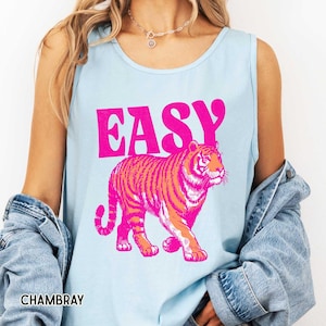 K&ouml;nnte beinhalten: Hellblaues Tanktop mit dem Wort "EASY" in leuchtend pinkfarbenen Blockbuchstaben &uuml;ber einer pink-orangenen Tigergrafik. Das Wort "CHAMBRAY" ist unten im Bild wei&szlig; gedruckt.