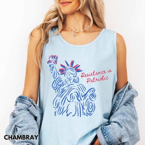 Pu&ograve; includere: Canotta azzurra con una grafica della Statua della Libert&agrave; in blu e rosso, con la scritta "Resistance is Patriotic". La canotta &egrave; realizzata in un materiale morbido.