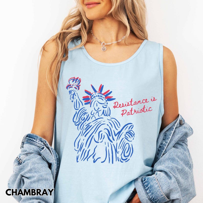 Pu&ograve; includere: Canotta azzurra con una grafica della Statua della Libert&agrave; in blu e rosso, con la scritta "Resistance is Patriotic". La canotta &egrave; realizzata in un materiale morbido.