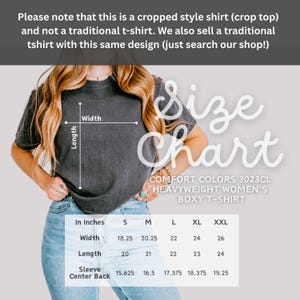 Pode incluir: Uma camiseta cinza escuro cortada com uma tabela de tamanhos. A tabela fornece medidas em cent&iacute;metros para largura, comprimento e centro das costas da manga para os tamanhos S a XXL. A camisa &eacute; Comfort Colors 3023CL Heavyweight Women's Boxy T-Shirt.