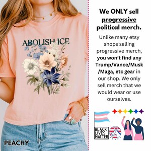 May include: Peach-colored t-shirt with the text "ABOLISH ICE" above a floral design in blue, white, and peach tones. The shirt also has the word "PEACHY" at the bottom. The image includes text about progressive political merchandise.