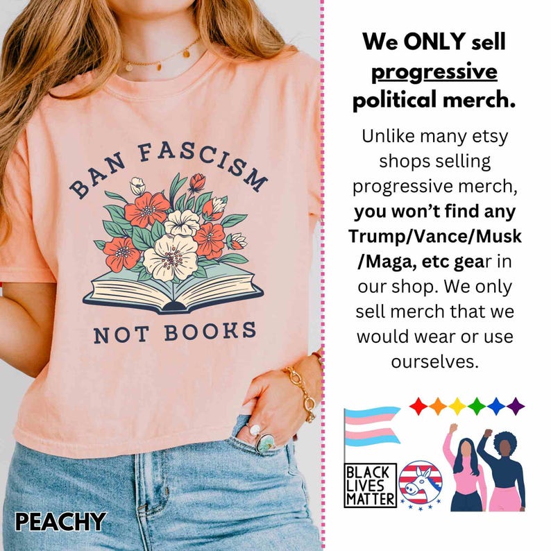 Op de afbeelding: Perzikkleurig T-shirt met de tekst "BAN FASCISM NOT BOOKS" boven een bloemenillustratie. Het shirt heeft ook het woord "PEACHY" aan de onderkant. Het shirt maakt deel uit van een progressieve politieke merch-collectie.