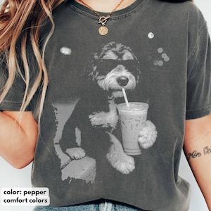 K&ouml;nnte beinhalten: Pfefferfarbenes T-Shirt mit einer schwarz-wei&szlig;en Grafik eines Hundes mit Sonnenbrille, der aus einem transparenten Eiskaffeebecher mit Strohhalm trinkt. Der Text "comfort colors" befindet sich am unteren Rand des Bildes.