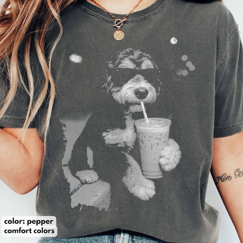 K&ouml;nnte beinhalten: Pfefferfarbenes T-Shirt mit einer schwarz-wei&szlig;en Grafik eines Hundes mit Sonnenbrille, der aus einem transparenten Eiskaffeebecher mit Strohhalm trinkt. Der Text "comfort colors" befindet sich am unteren Rand des Bildes.