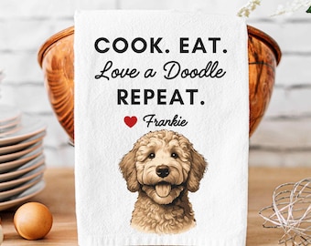 May include: White kitchen towel with the text "COOK. EAT. Love a Doodle REPEAT." and a red heart with the name "Frankie" below. A brown and white doodle dog is pictured below the text.