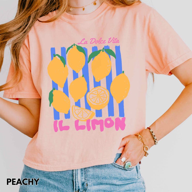 May include: Peach-colored t-shirt with a lemon graphic. The design includes yellow lemons, blue stripes, and the text "La Dolce Vita" and "IL LIMON". The word "PEACHY" is printed at the bottom left.