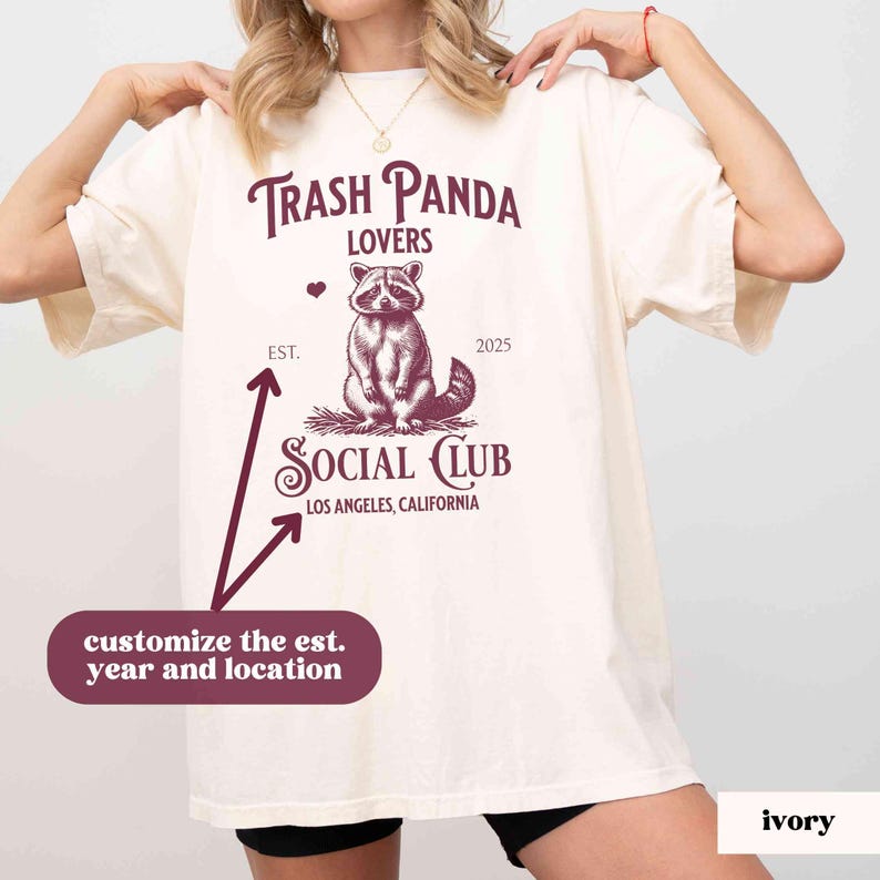 May include: A white t-shirt with a burgundy graphic of a raccoon with the text "Trash Panda Lovers" and "Social Club" with the text "Los Angeles, California" below. The text "Est." and "2025" are above the raccoon graphic.