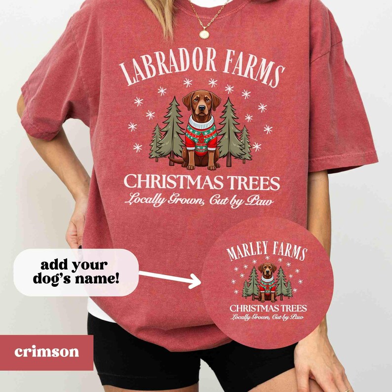 K&ouml;nnte beinhalten: Ein rotes T-Shirt mit einer wei&szlig;en Grafik eines braunen Labrador Retrievers, der einen rot-wei&szlig;en Pullover vor einem Weihnachtsbaum tr&auml;gt. Der Text "Labrador Farms" befindet sich &uuml;ber dem Hund und "Christmas Trees Locally Grown, Cut by Paw" unter dem Hund. Der Text "Marley Farms" befindet sich in einem Kreis auf der rechten Seite des Bildes mit der gleichen Grafik des Hundes und des Weihnachtsbaums. Der Text "Christmas Trees Locally Grown, Cut by Paw" befindet sich unter dem Hund.