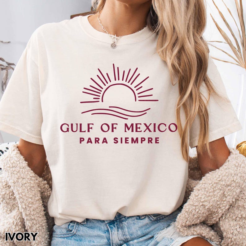 May include: A white t-shirt with a burgundy graphic of a sun setting over waves. The text "GULF OF MEXICO PARA SIEMPRE" is printed below the graphic.