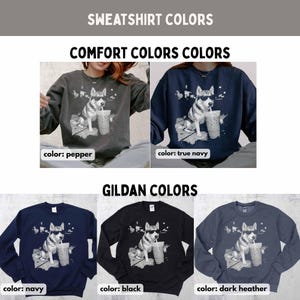 May include: Sweatshirt color options are displayed. The image shows a variety of sweatshirts in different colors, including pepper, true navy, navy, black, and dark heather. Each sweatshirt features a graphic of a dog wearing sunglasses and drinking from a cup.
