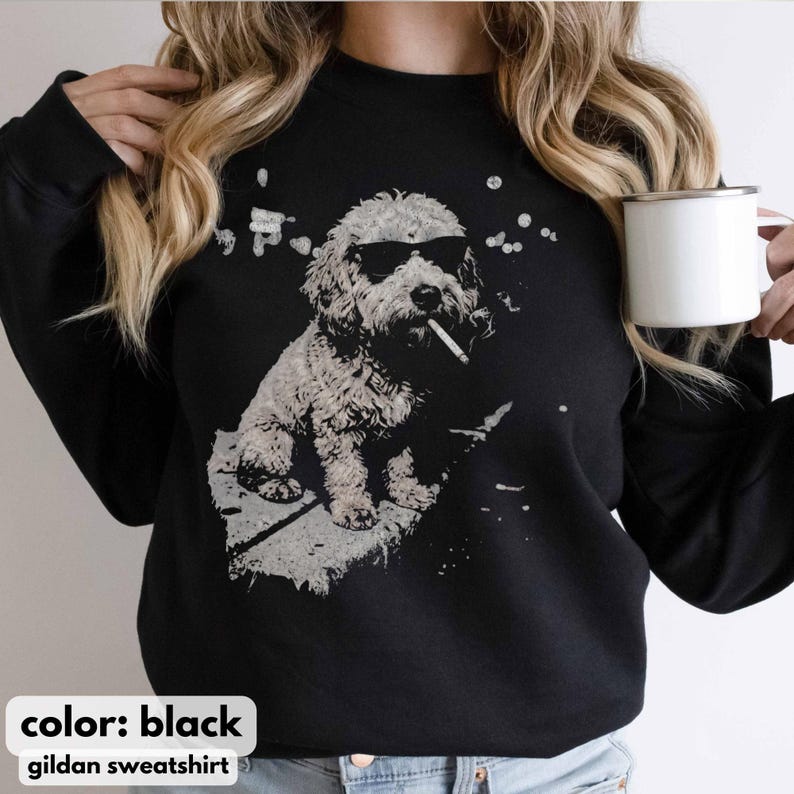 May include: Black Gildan sweatshirt featuring a graphic of a dog wearing sunglasses and smoking a cigarette. The dog is depicted in a grayscale illustration. The text "color: black" and "gildan sweatshirt" are at the bottom.
