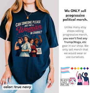 May include: True navy blue t-shirt with the text "CAN SOMEONE PLEASE JUST PUT A Woman IN CHARGE?" and an illustration of four women. The shirt also features the text "NO KINGS IN AMERICA". The shirt is part of a progressive political merch collection.