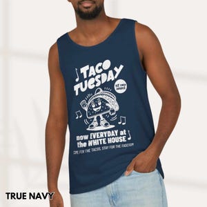 May include: Navy blue tank top with a white graphic that reads "TACO TUESDAY" with a dancing taco illustration. The text "now EVERYDAY at the WHITE HOUSE" and "COME FOR THE TACOS, STAY FOR THE FASCISM" is also included.