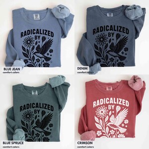 May include: Four long-sleeved sweatshirts in blue jean, denim, blue spruce, and crimson. Each shirt features the text "RADICALIZED BY" above a floral and bird graphic in black. The sleeves are cuffed with a soft, fuzzy material.