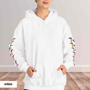 May include: White hooded sweatshirt with a kangaroo pocket and a row of colorful dachshund dogs printed on each sleeve.