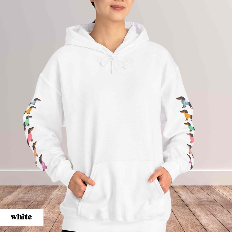 May include: White hooded sweatshirt with a kangaroo pocket and a row of colorful dachshund dogs printed on each sleeve.