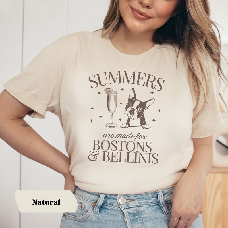 Puede incluir: Una camiseta beige con un dise&ntilde;o gr&aacute;fico marr&oacute;n que dice "Summers are made for Bostons & Bellinis". El gr&aacute;fico tambi&eacute;n incluye una imagen de dibujos animados de un perro Boston Terrier y una copa de champ&aacute;n.
