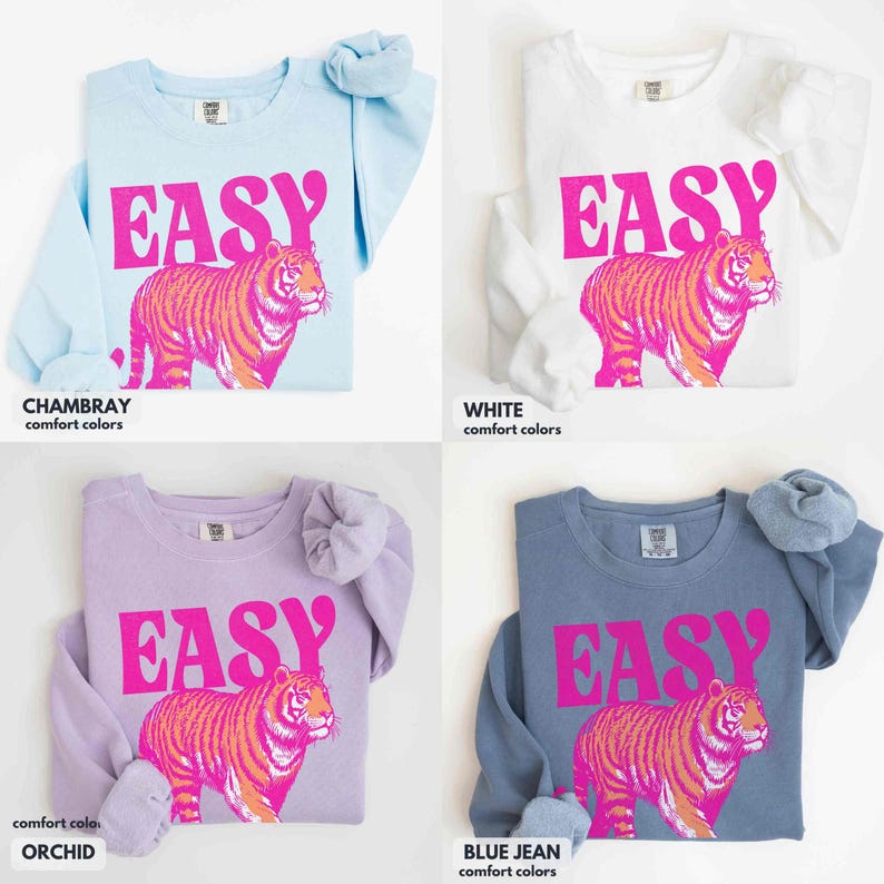 May include: Four long-sleeve crewneck sweatshirts in chambray, white, orchid, and blue jean colors. Each sweatshirt features the word EASY in bold pink letters above a graphic of a tiger with orange and pink stripes on the front chest area.