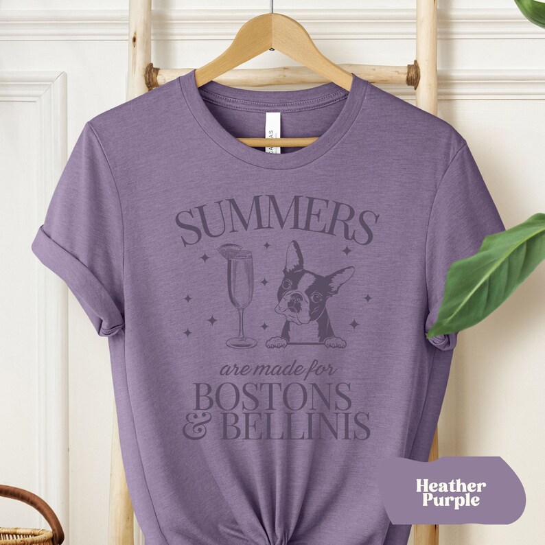 Puede incluir: Una camiseta morada con el texto "SUMMERS are made for BOSTON & BELLINIS" y un gr&aacute;fico de un Boston Terrier mirando por encima de una copa de champ&aacute;n. El texto "Heather Purple" est&aacute; en la esquina inferior derecha.